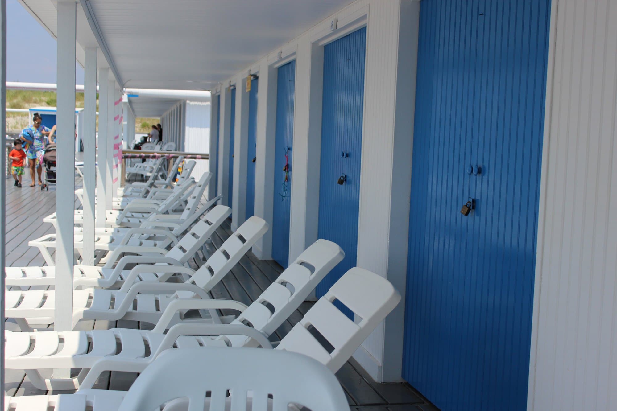 The covered walkway along a cabana row at The Sands, blue doors and white loungers on the gray deck